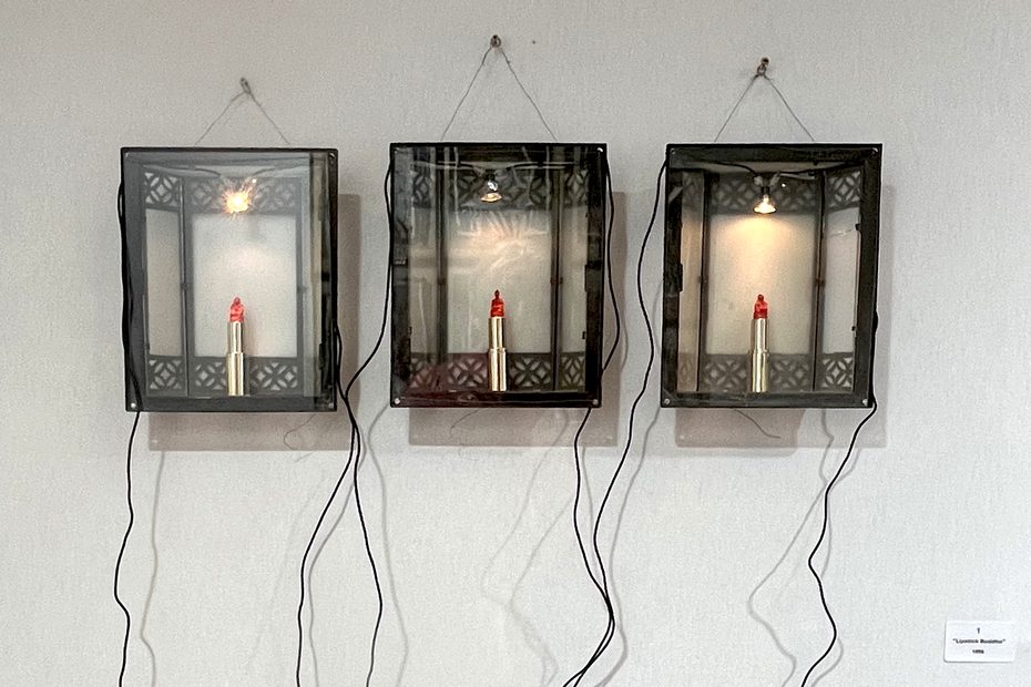 Lipstick Buddha, 1996 – Three illuminated display boxes containing Buddha figures hand-carved directly into lipstick.