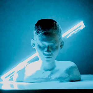 Introspection, 2015: ceramic bust with closed eyes and bowed head, lit by a diagonal blue neon tube.